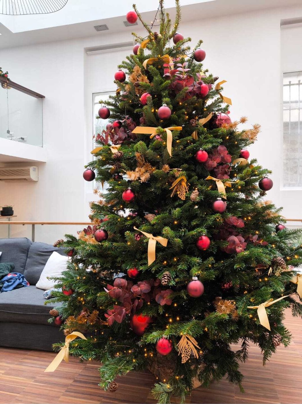 Sapin de Noël décoré en bordeaux et or dans un espace de détente d'entreprise